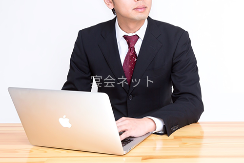 ノートパソコンで予約手続きをする男性