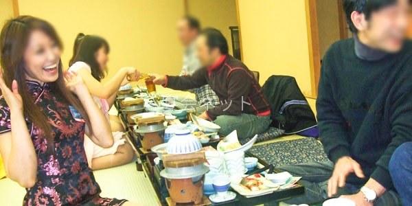 食の場にコンパニオンが笑顔でお酌する様子